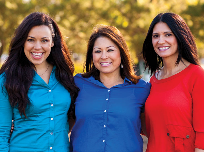 Three lady friends smiling outside.